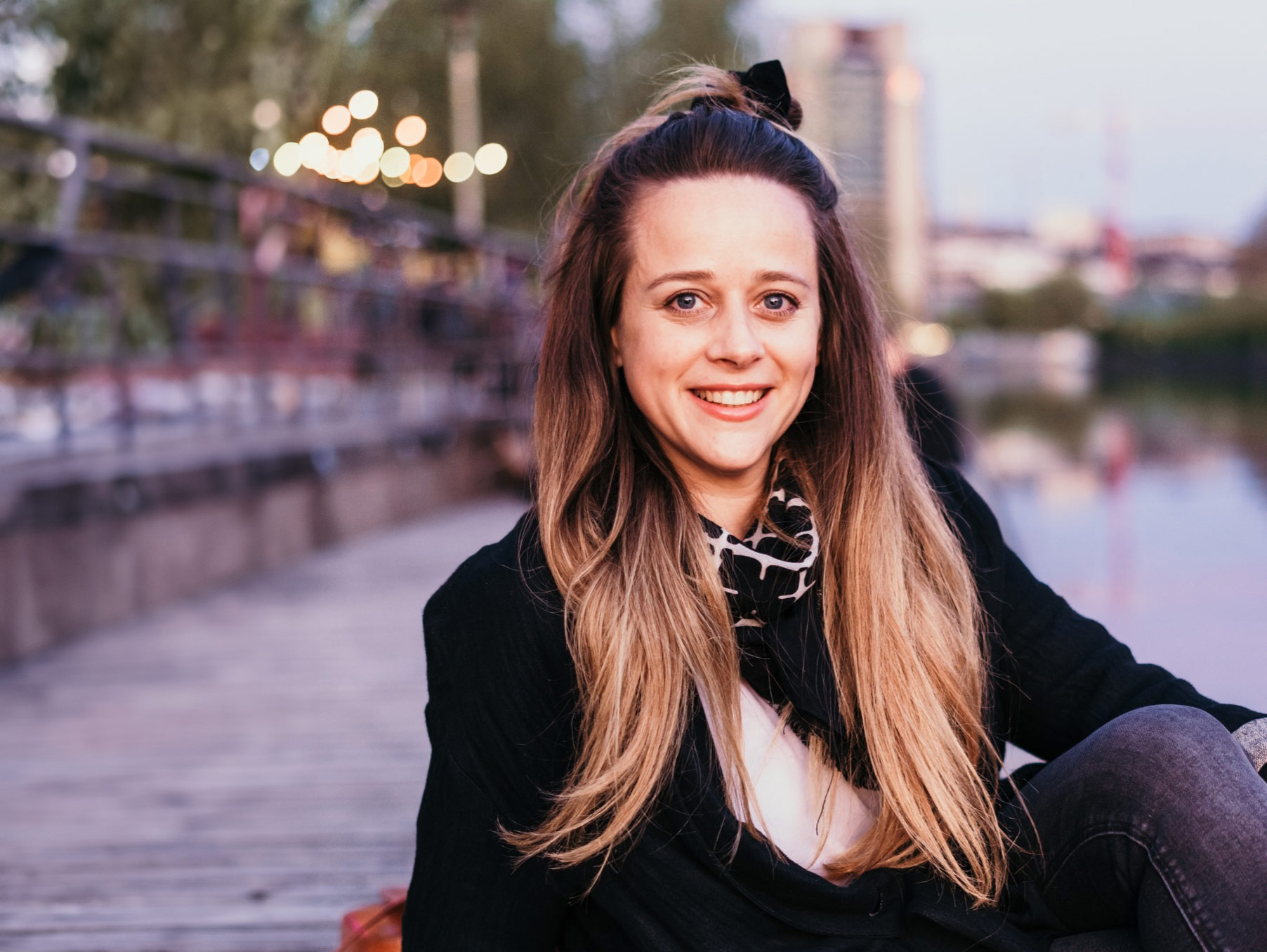 Nina abends in der Stadt am Fluss sitzend